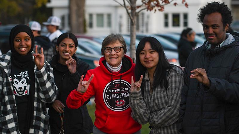 President Wacker doing the sign of the Husky with students